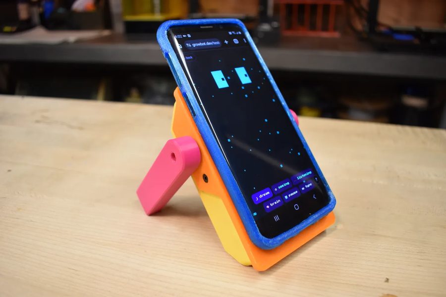 A finished GrowBot standing upright on a table, phone mounted as its face showing the live controller.